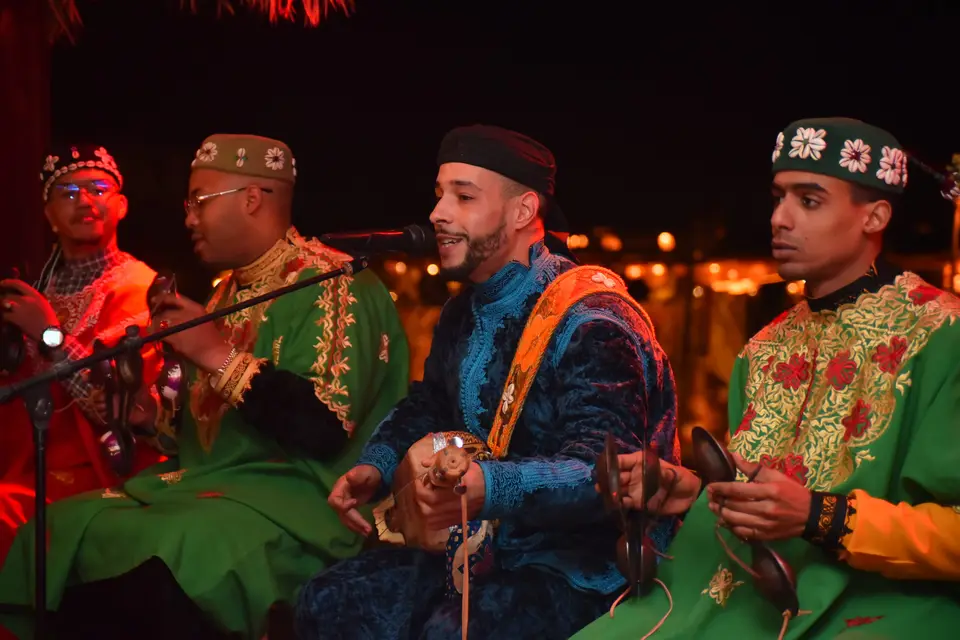 Gnaoua musicians in embroidered robes playing and singing at night