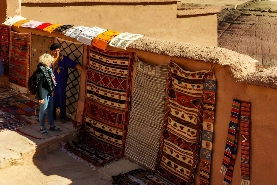 Woven rugs for sale draped along a mud-brick wall